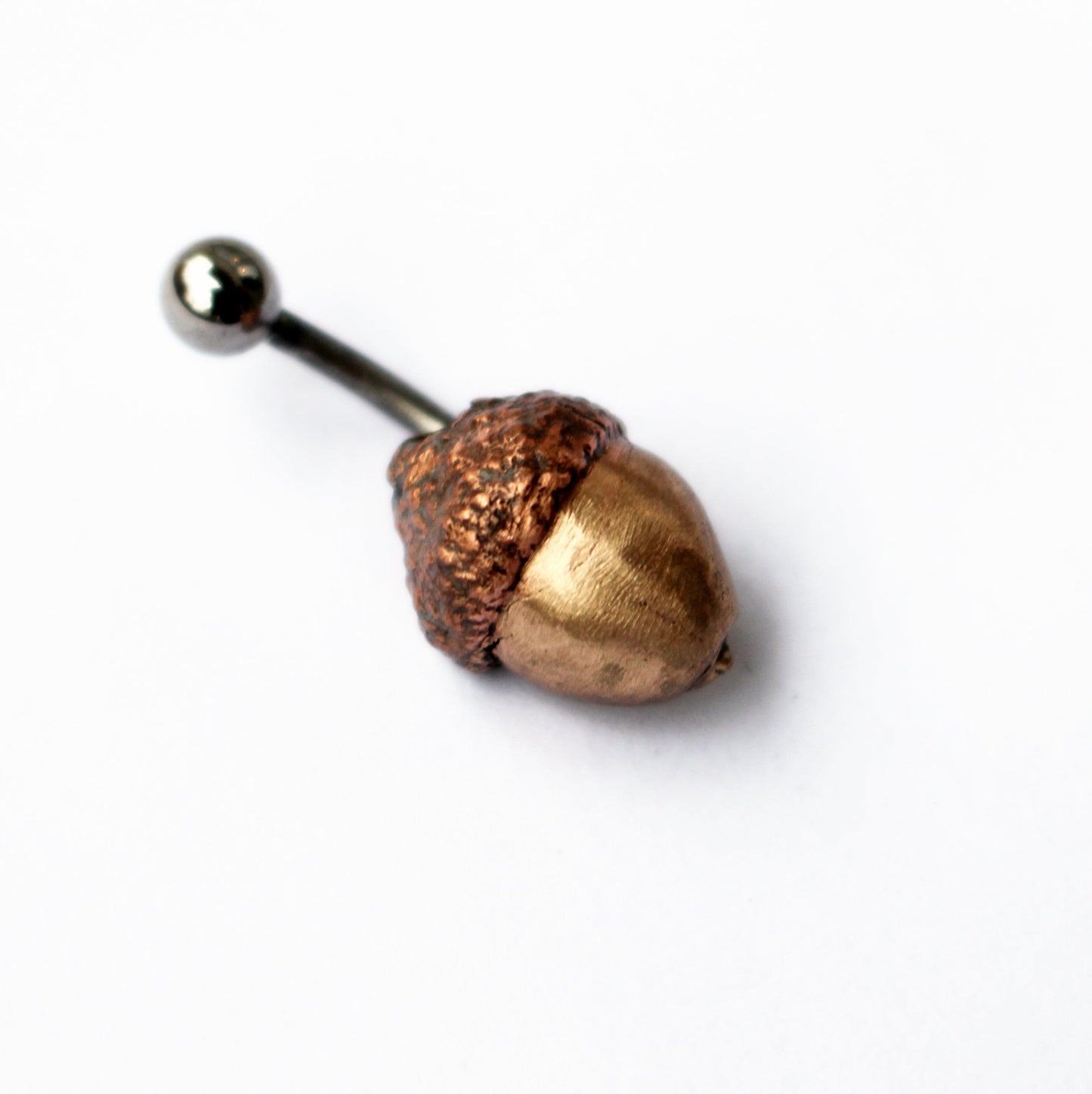 Acorn belly button ring with a bronze nut, copper cap, and a curved barbell
