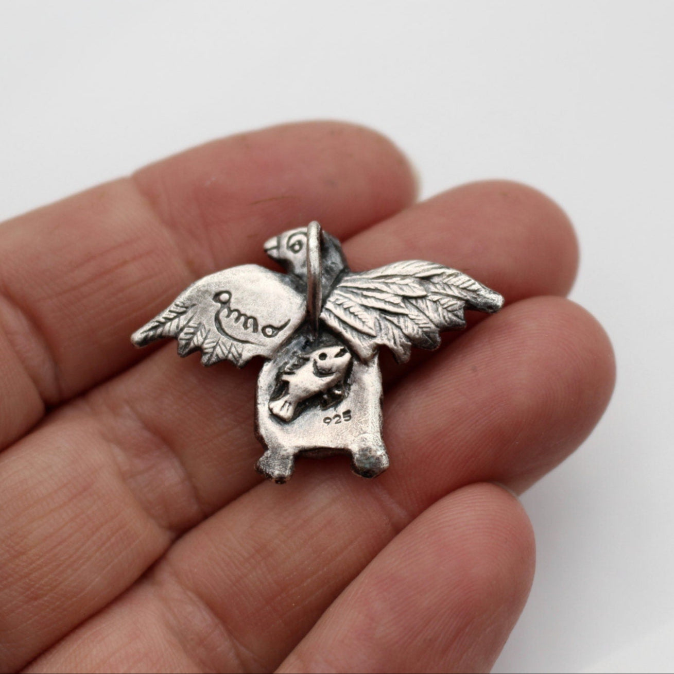 silver pingvin smycke med en liten fisk skulpterad i magen