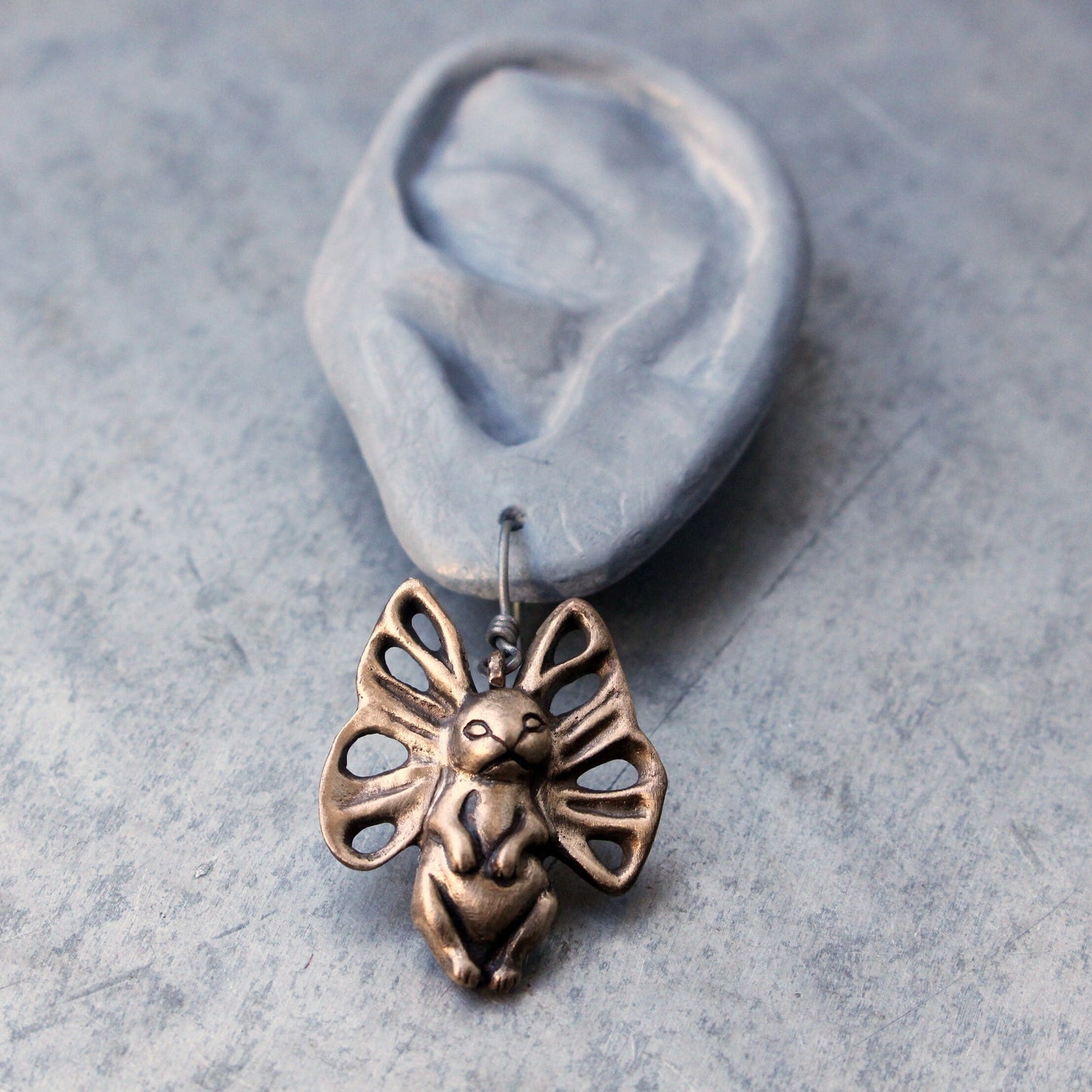 bronze earring with a bunny -fly creature with butterfly wings for ears