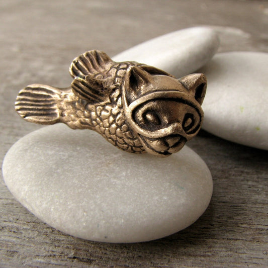 Bronze fish-shaped object on a white stone surface