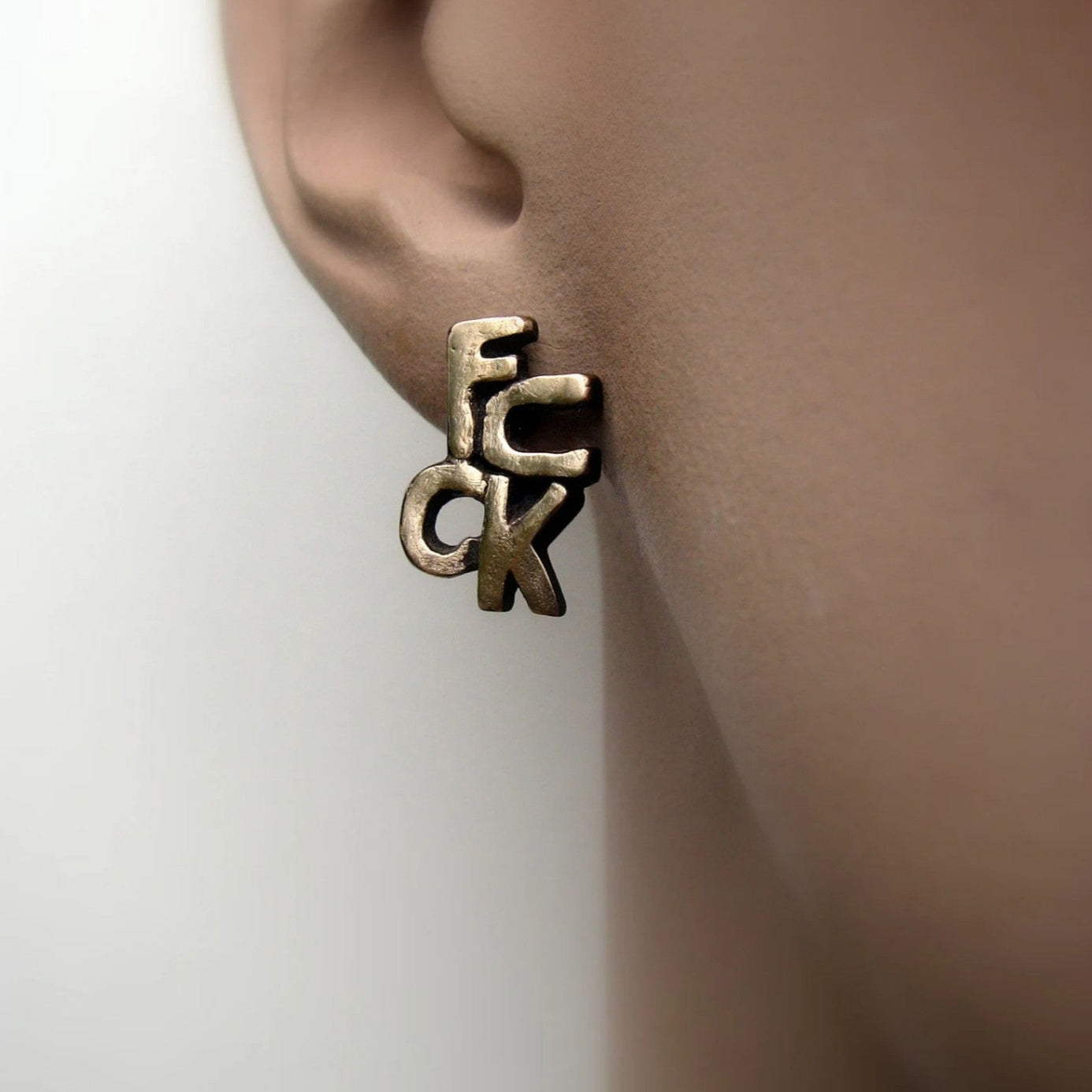 a earring in bronze and titanium that say fuck