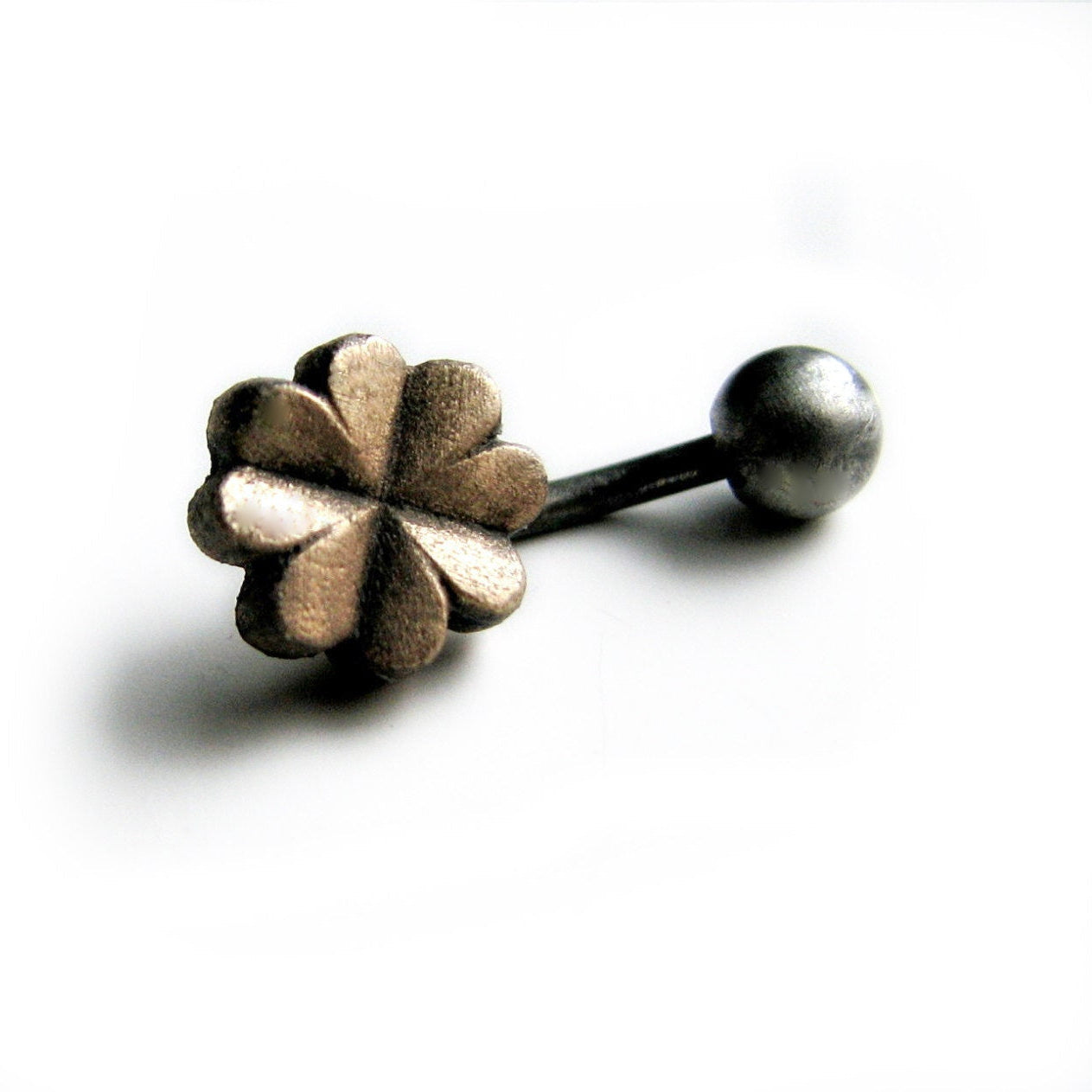 A belly button ring with a four leaf clover-shaped charm attached to a curved barbell