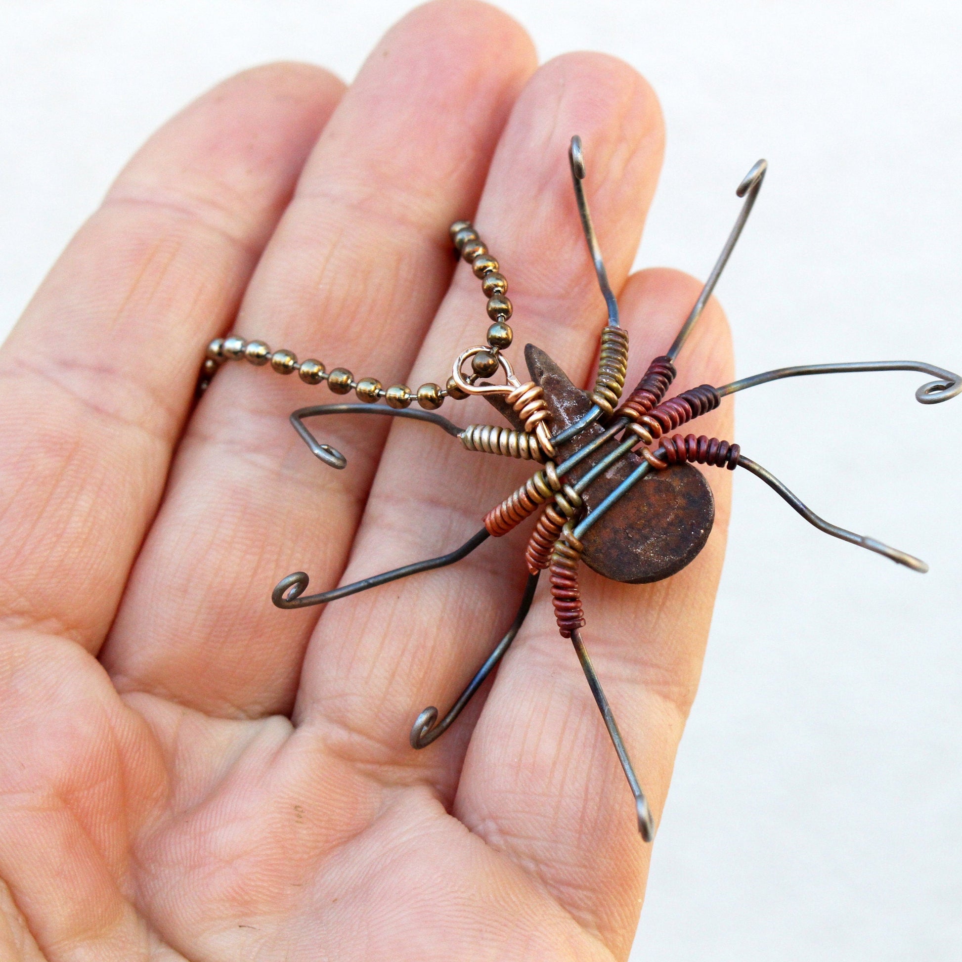 Handmade wire sculpture of a spider creature held in a hand