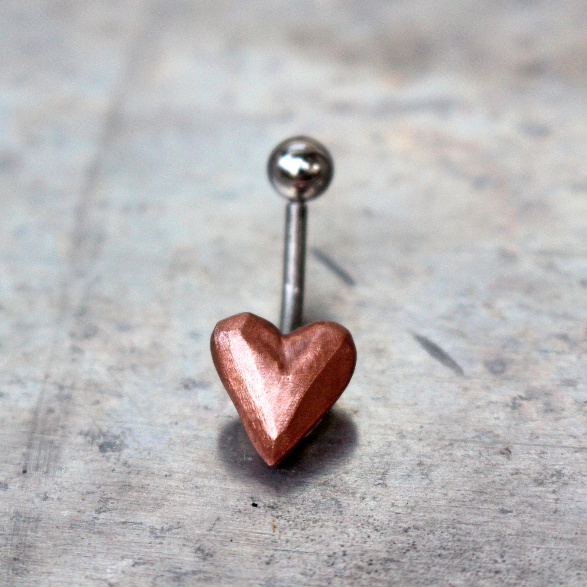 belly button ring with pink puffy copper heart attached to a curved barbell.
