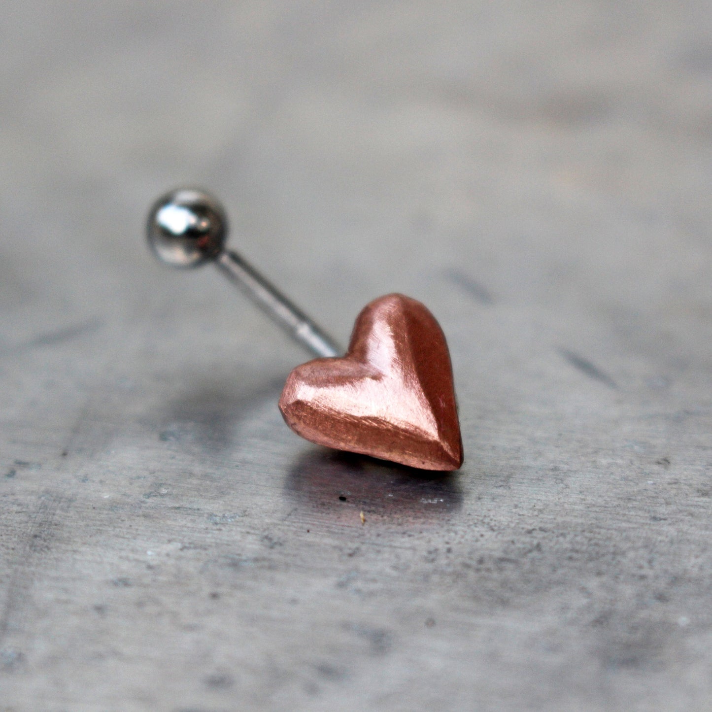 belly button ring with pink puffy copper heart attached to a curved barbell.