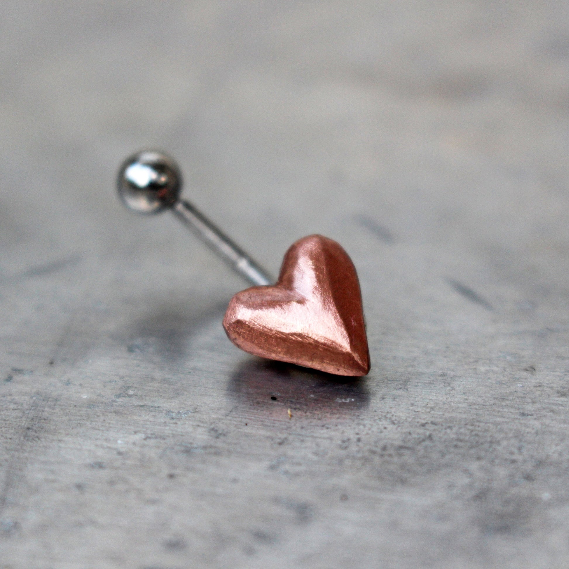 belly button ring with pink puffy copper heart attached to a curved barbell.