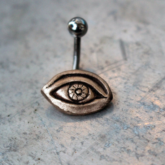 A belly button ring with a bronze eye design attached to a curved barbell.