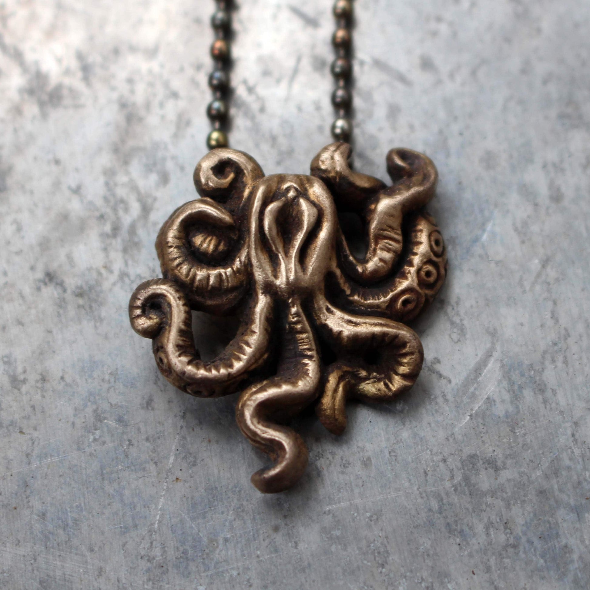 This image features a distinctive necklace with a bronze-colored pendant, depicting a whimsical, mature tentacle monster. The pendant is intricately sculpted, showcasing swirling tentacles and a unique, elegant shape.