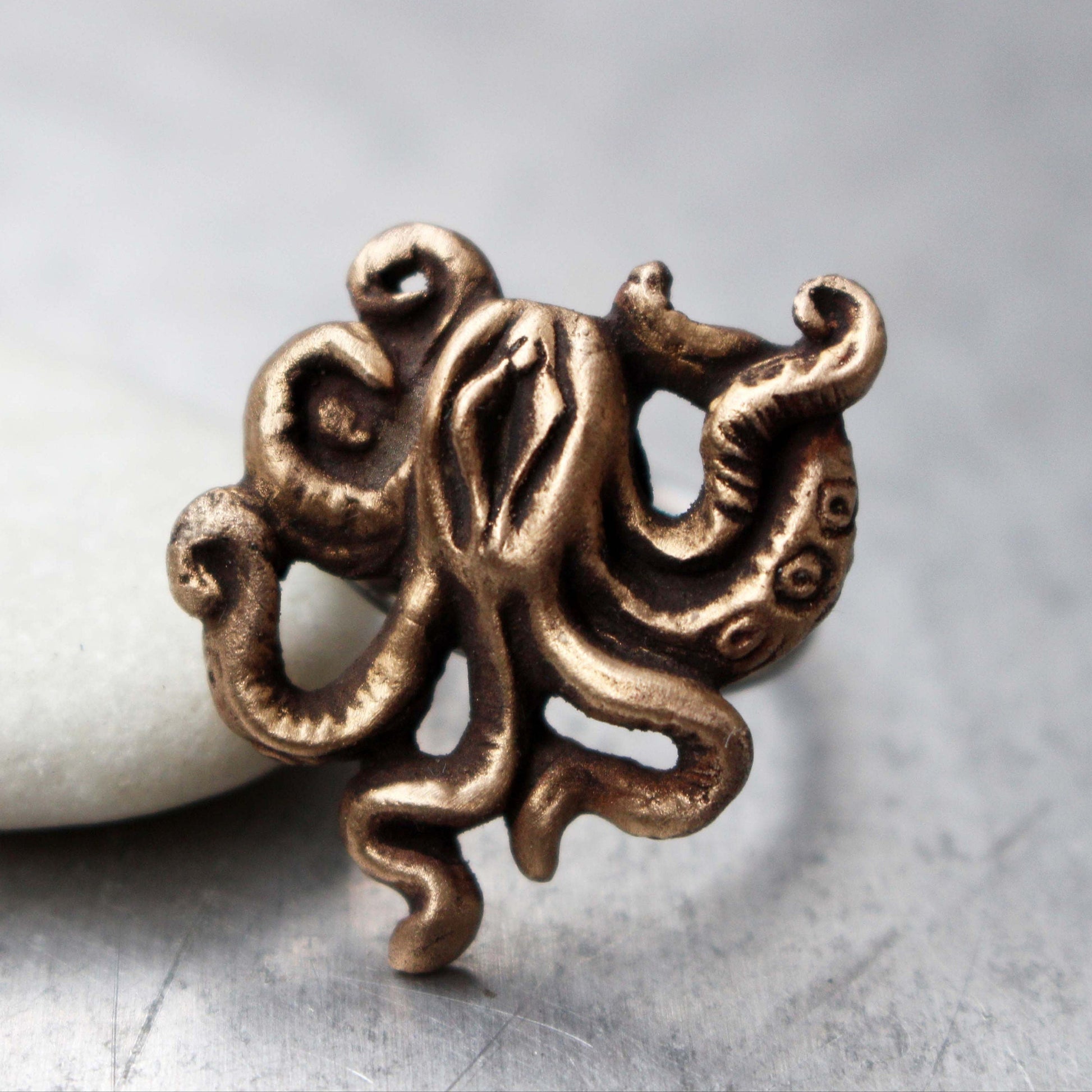 This image features a unique and artistic ring known as the "Mature octopussy ring, labia art." It showcases a bronze sculpture of an octopus creature with swirling tentacles, crafted with meticulous detail.