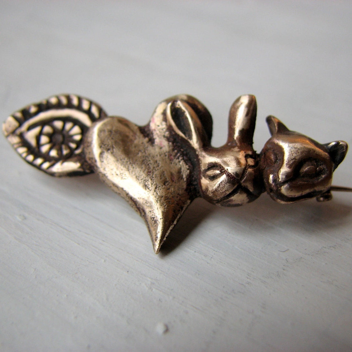Bronze brooch in the shape of a heart with a bunny and a cat, with the text 'I love animals'.