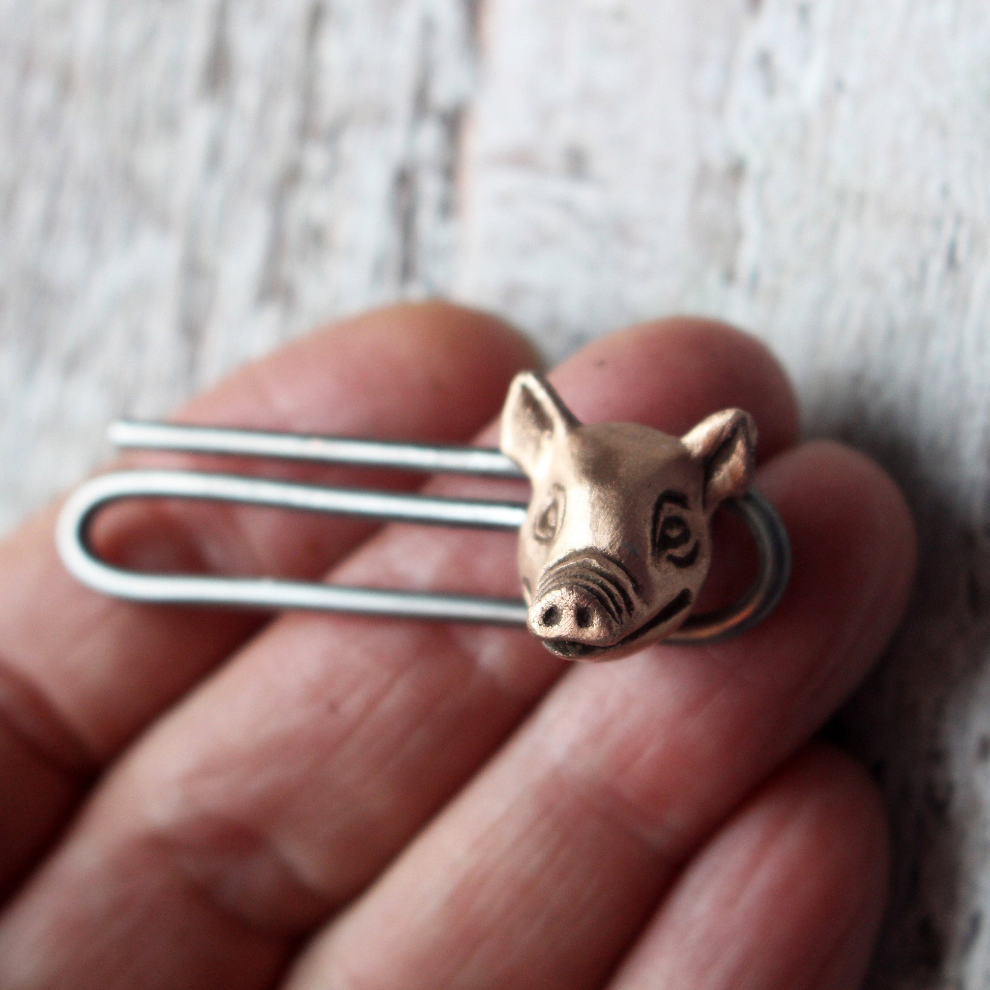 slipsnål  med ett grishuvud i koppar och klämma i stål