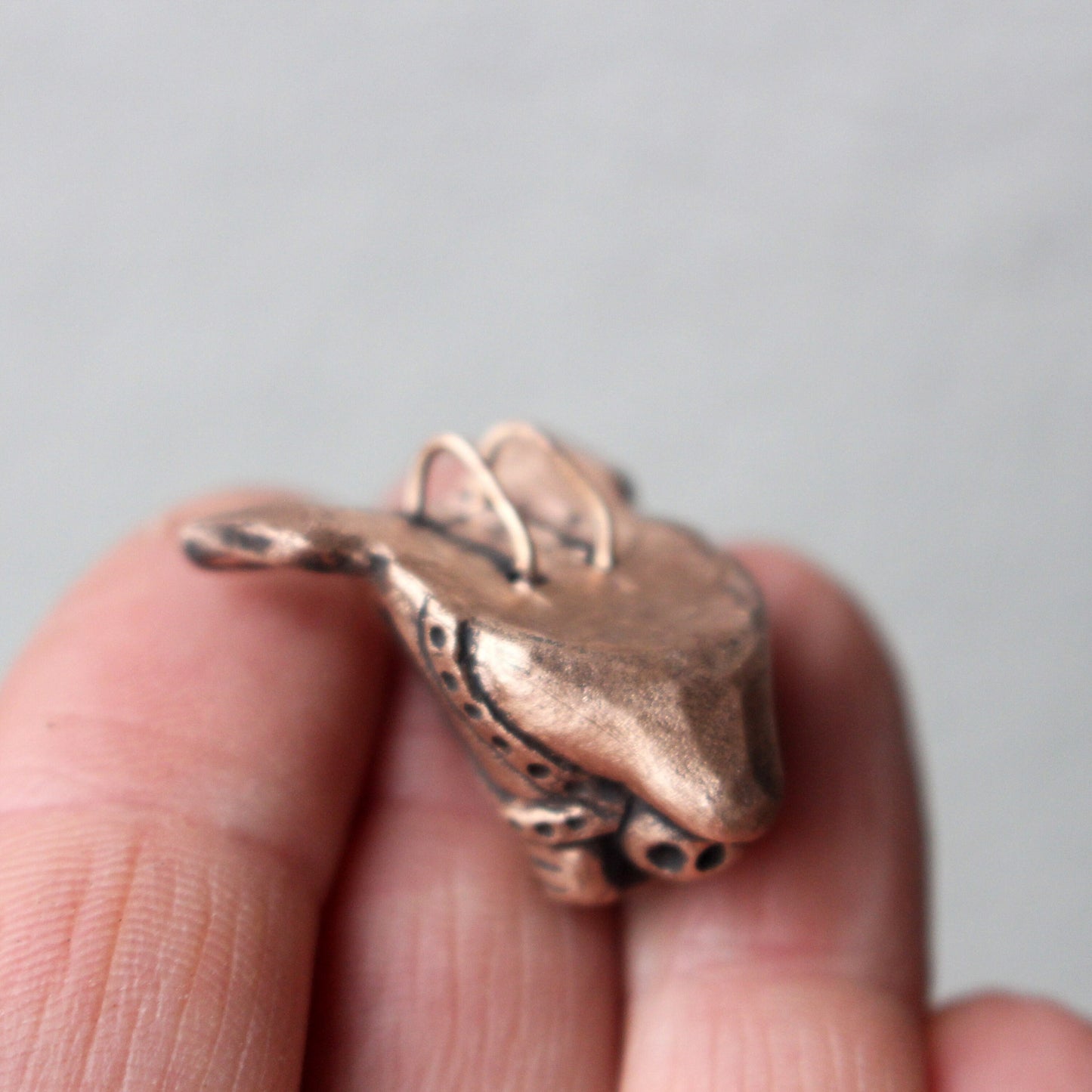 A bronze and copper pendant with kinky pig with a ball gag harness