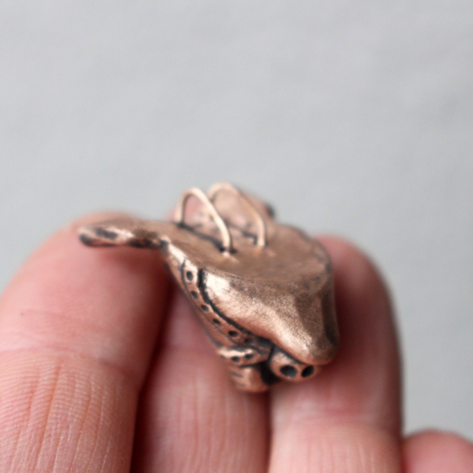 A bronze and copper pendant with kinky pig with a ball gag harness