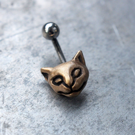 A belly button ring with a small bronze cat head attached to one end of a curved barbell.