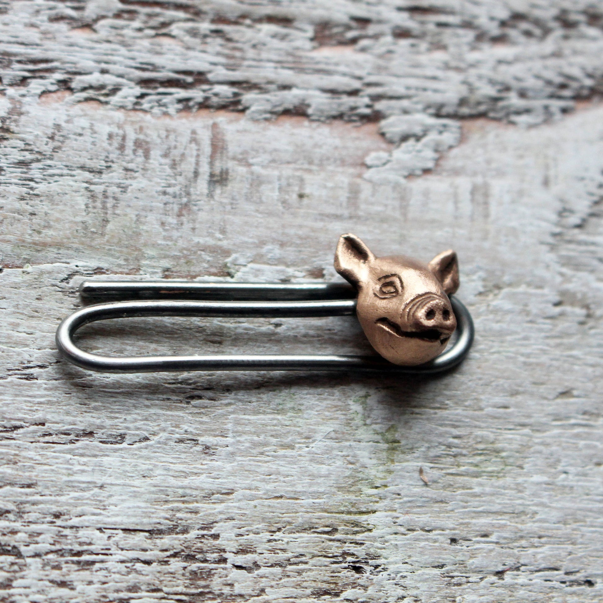 tie clip with a pig head design, made in copper with a stainless steel pin