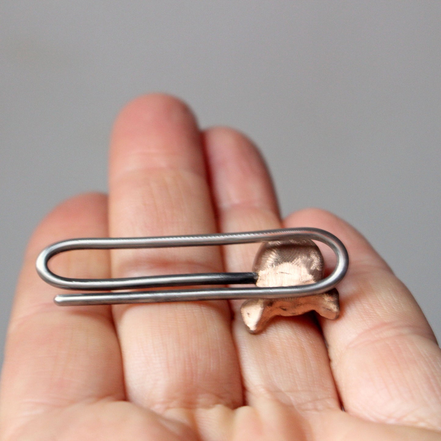 A tie clip with a pig head design, made in copper with a stainless steel pin, backside