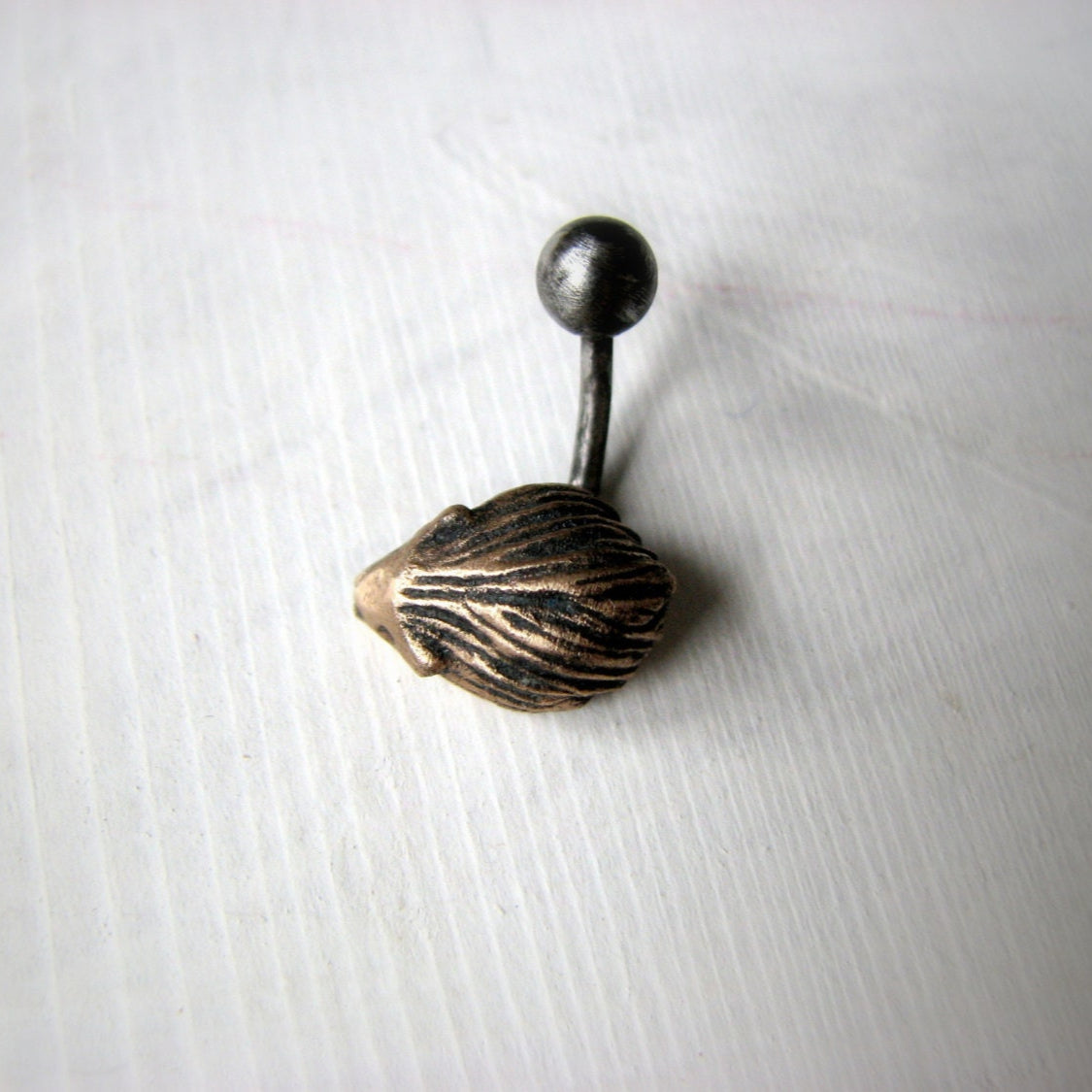 A belly button ring with a hedgehog in bronze and titanium