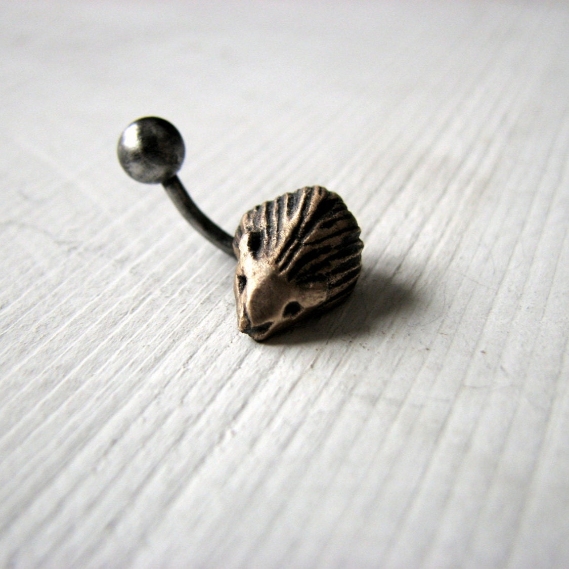 A belly button ring with a hedgehog- in bronze and titanium