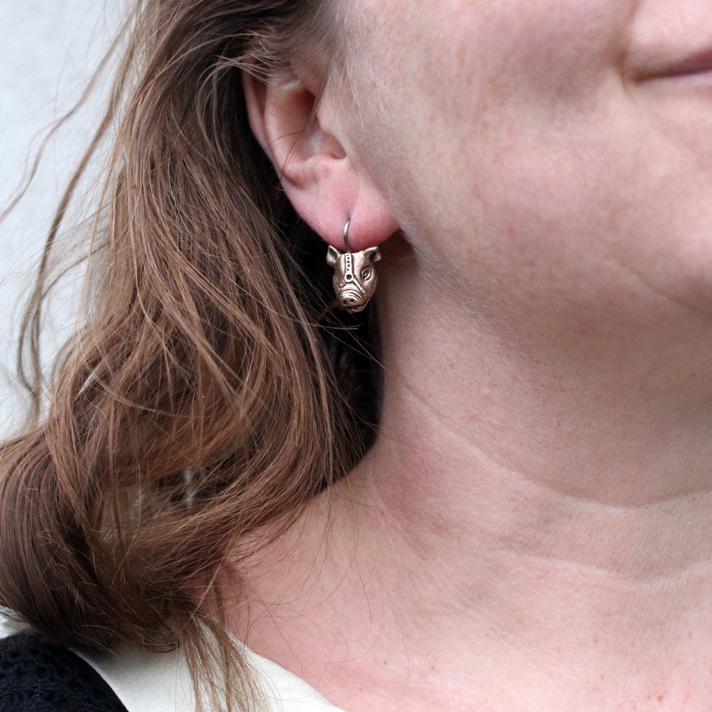 A bronze and copper earrings with kinky pig with a ball gag harness