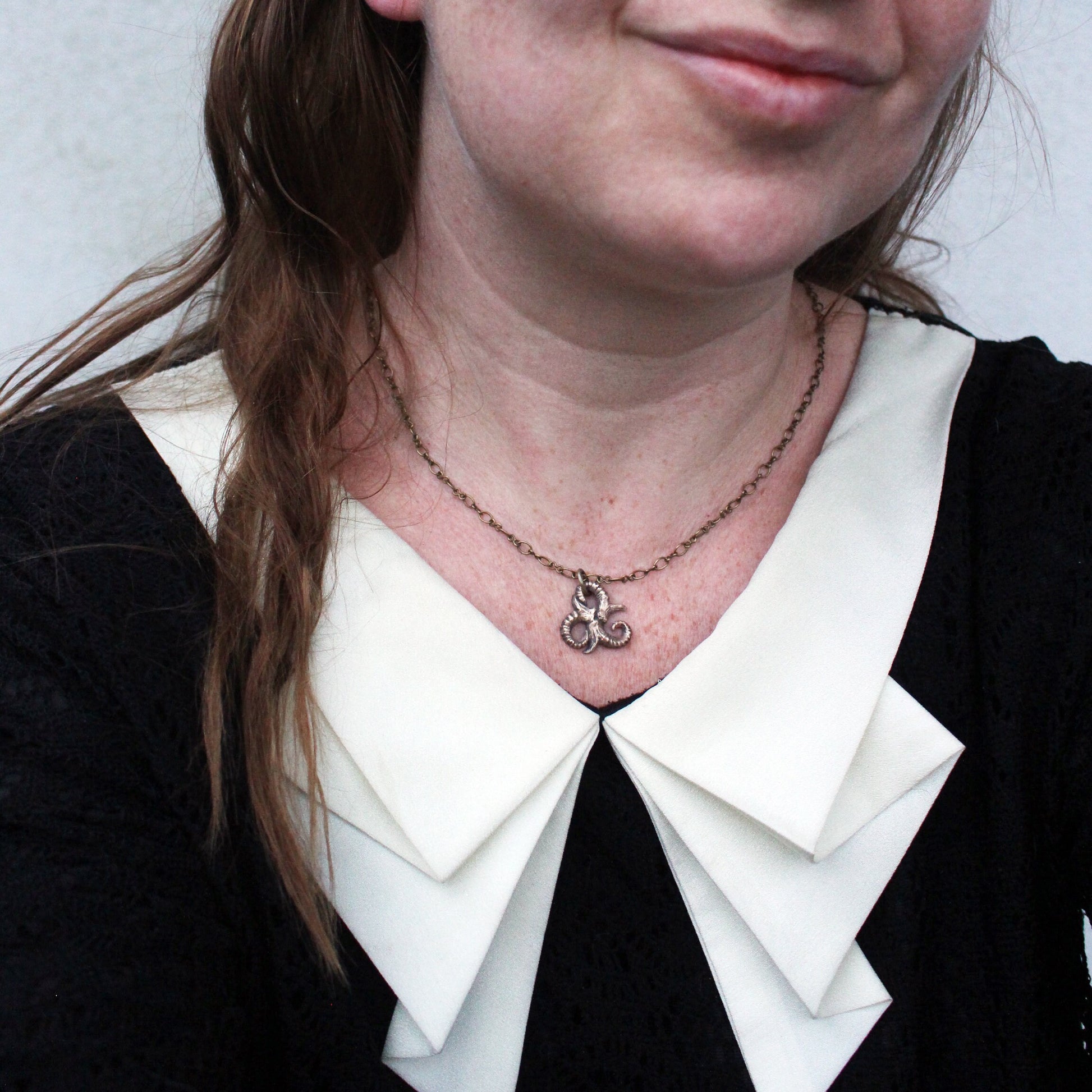 triskele bdsm symbol necklace worn by a person