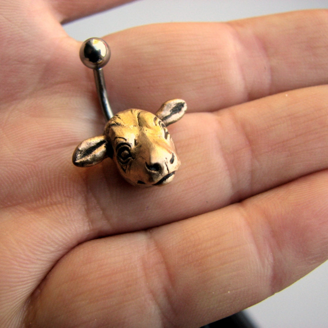 bronze cow belly button ring with a cow head on a curved barbell