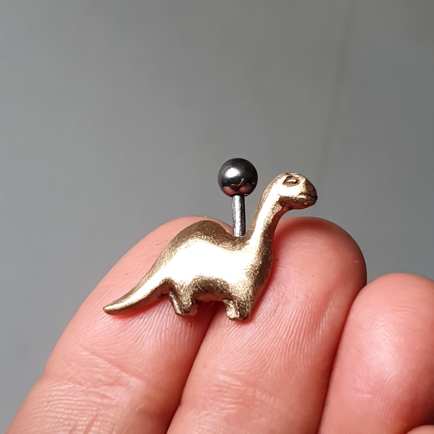 brons och titan navelsmycke med en brachiosaurus dinosaur