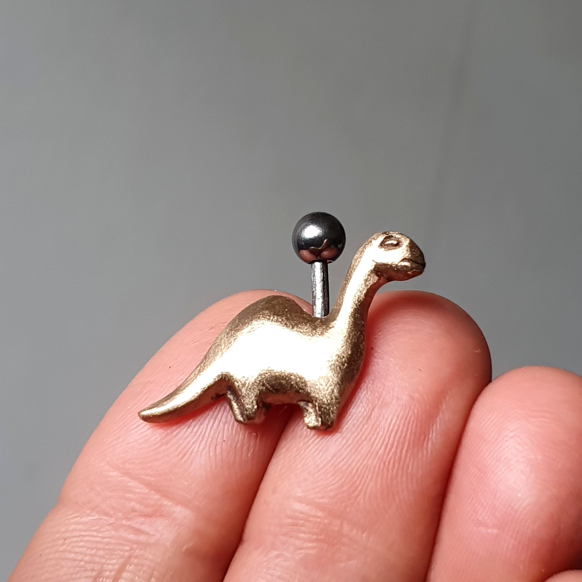 brons och titan navelsmycke med en brachiosaurus dinosaur