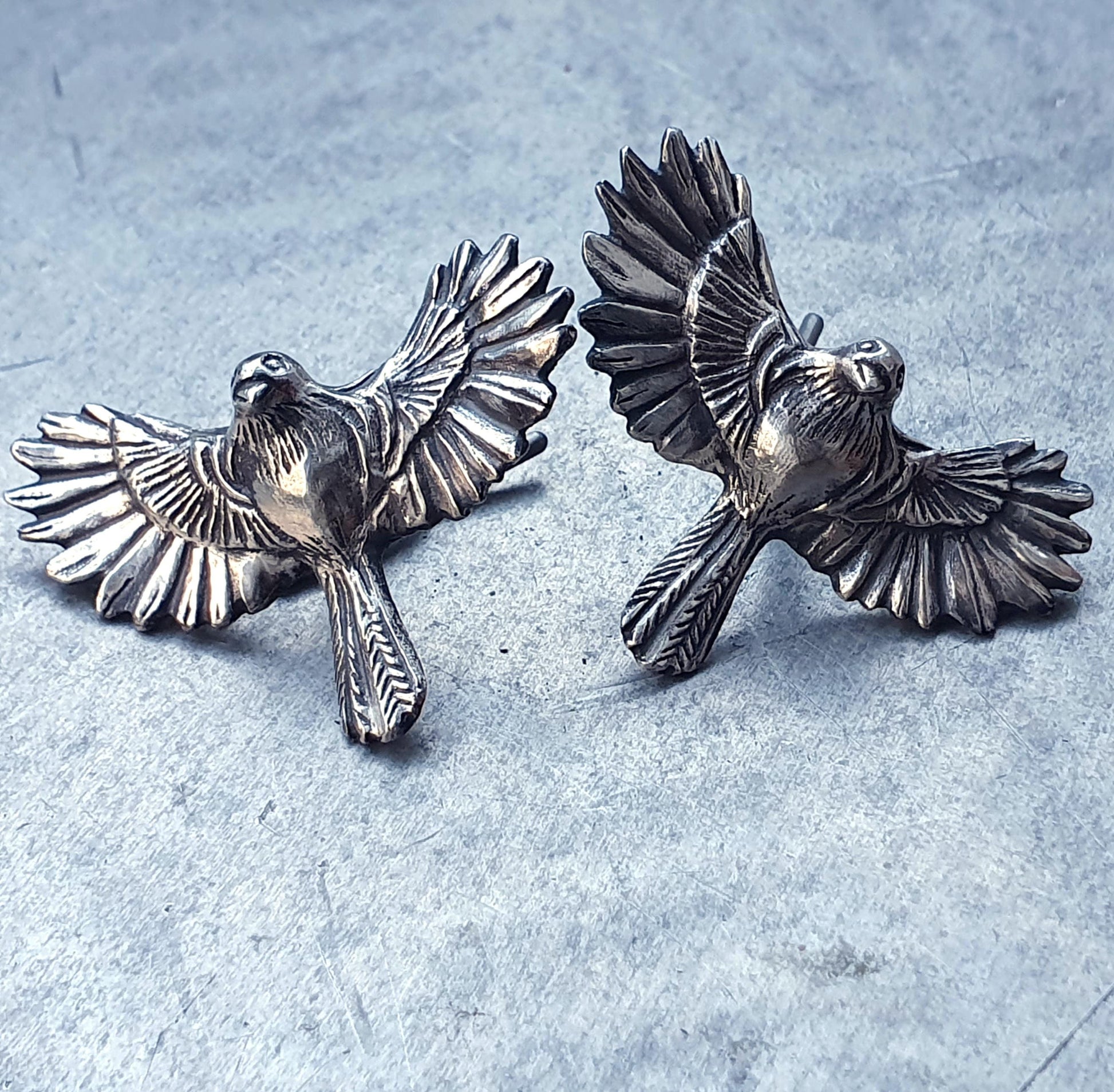 A pair of silver cufflinks with birds in mid-flight with wings spread