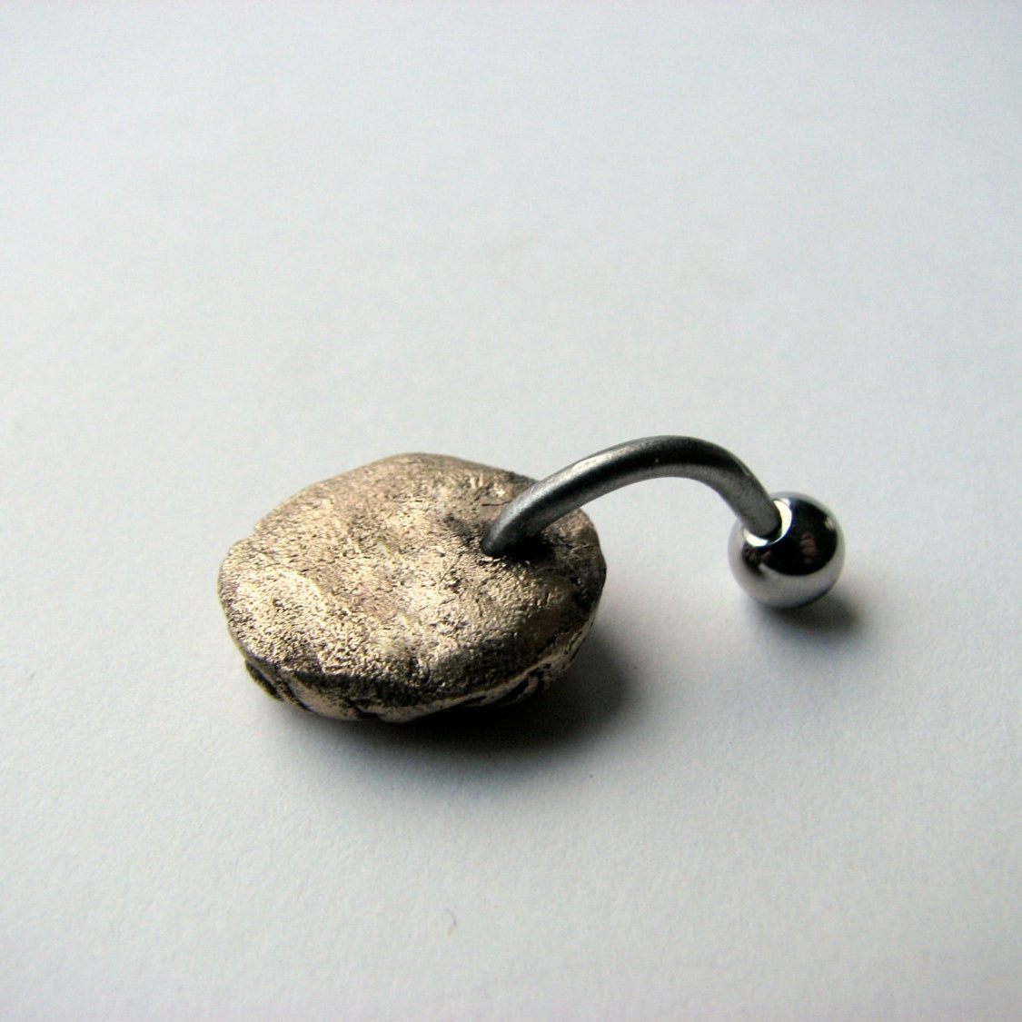 baksida, Navelpiercing smycke med en liten skulpterad hjärna i brons och titan stång