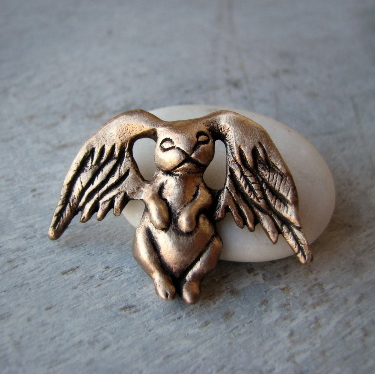 Bronze angel winged figure on a white stone surface
