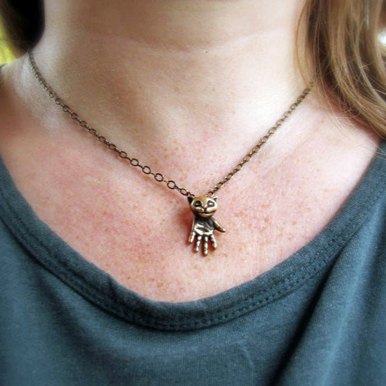 Necklace with a hand-shaped pendant worn by a person