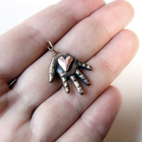 Bronze hand-shaped pendant with a pink copper heart in the palm