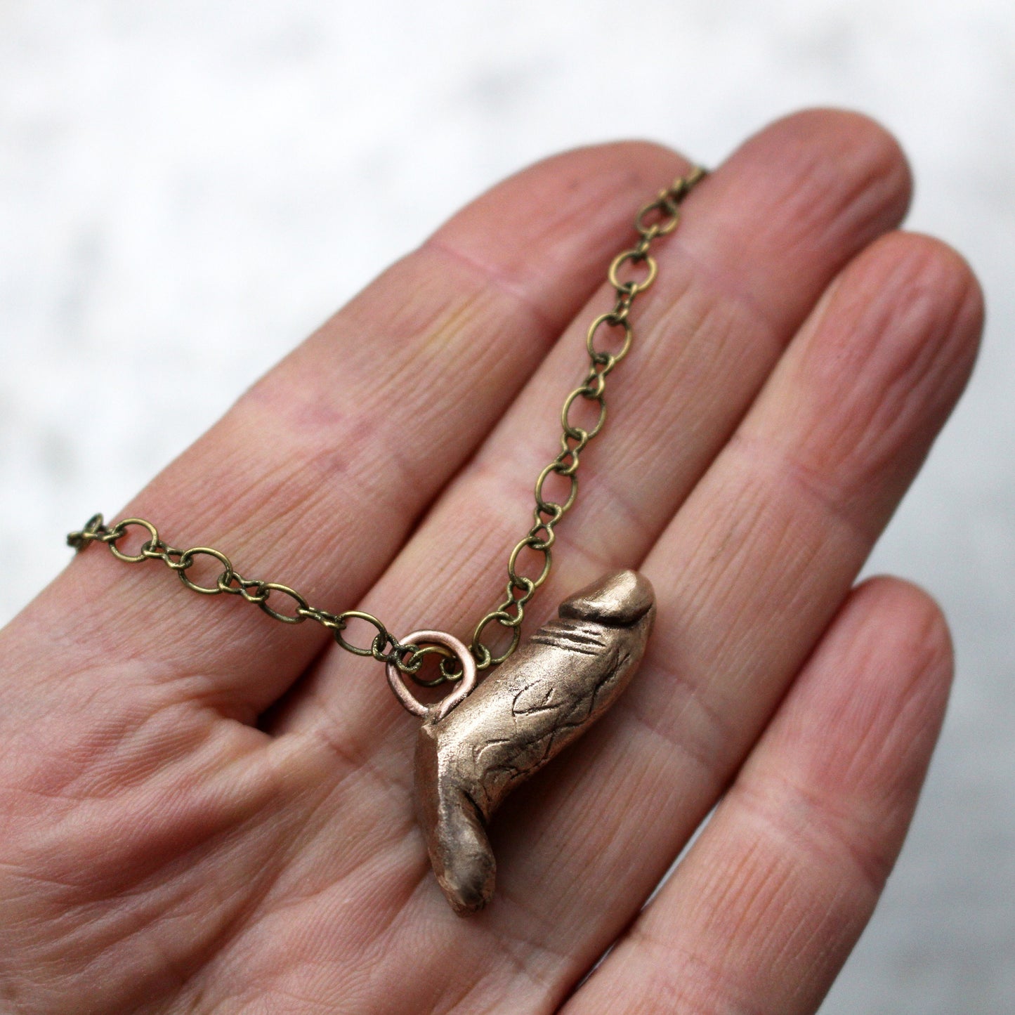 halsband med skulpterad bronskuk i en persons hand