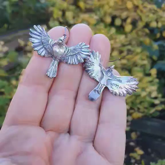 bird earrings in siver and titanium, figure of a lying girl on the backside of the birds