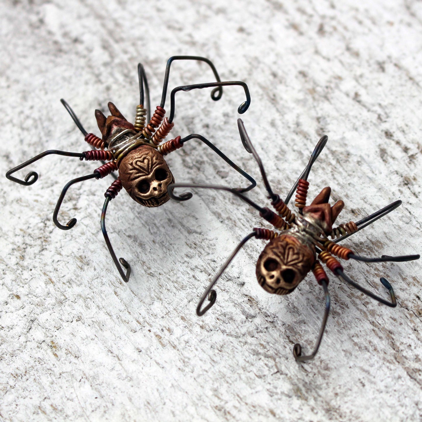 ett par spindelörhängen med döskallar på svarta änkan