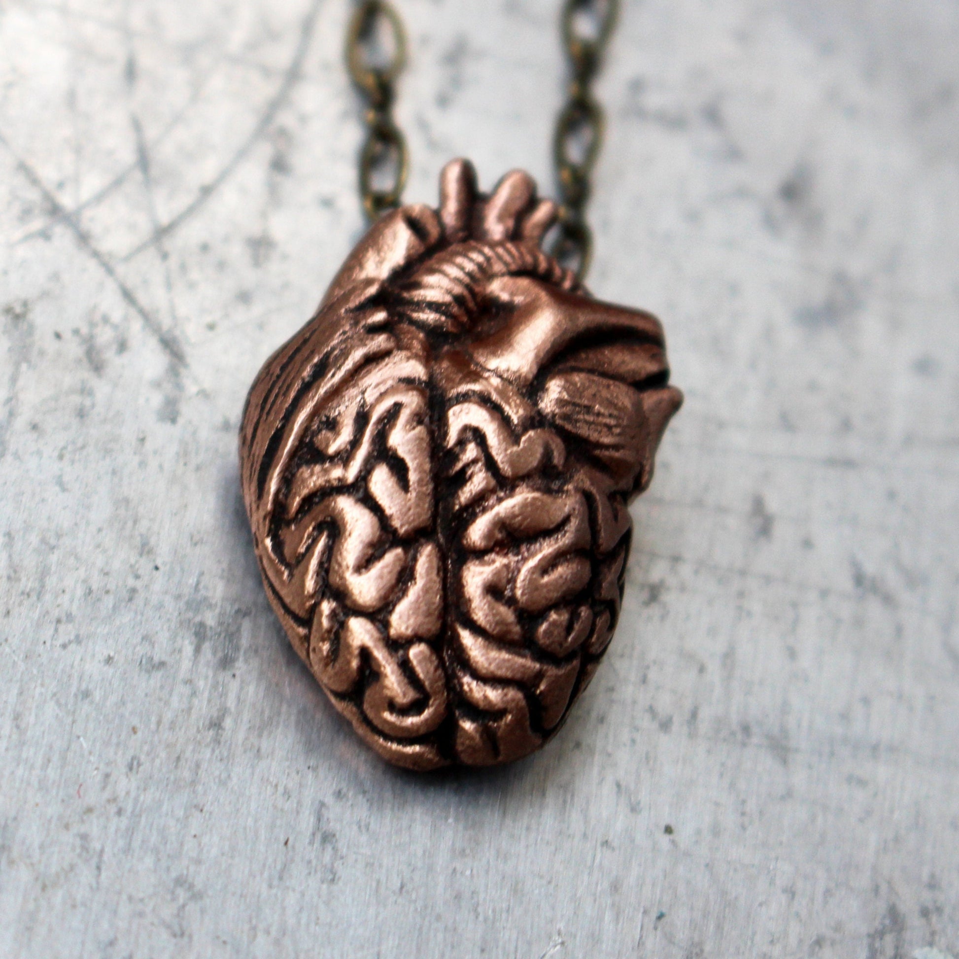 pendant with a mix of anatomical heart and brain sculpted in metal