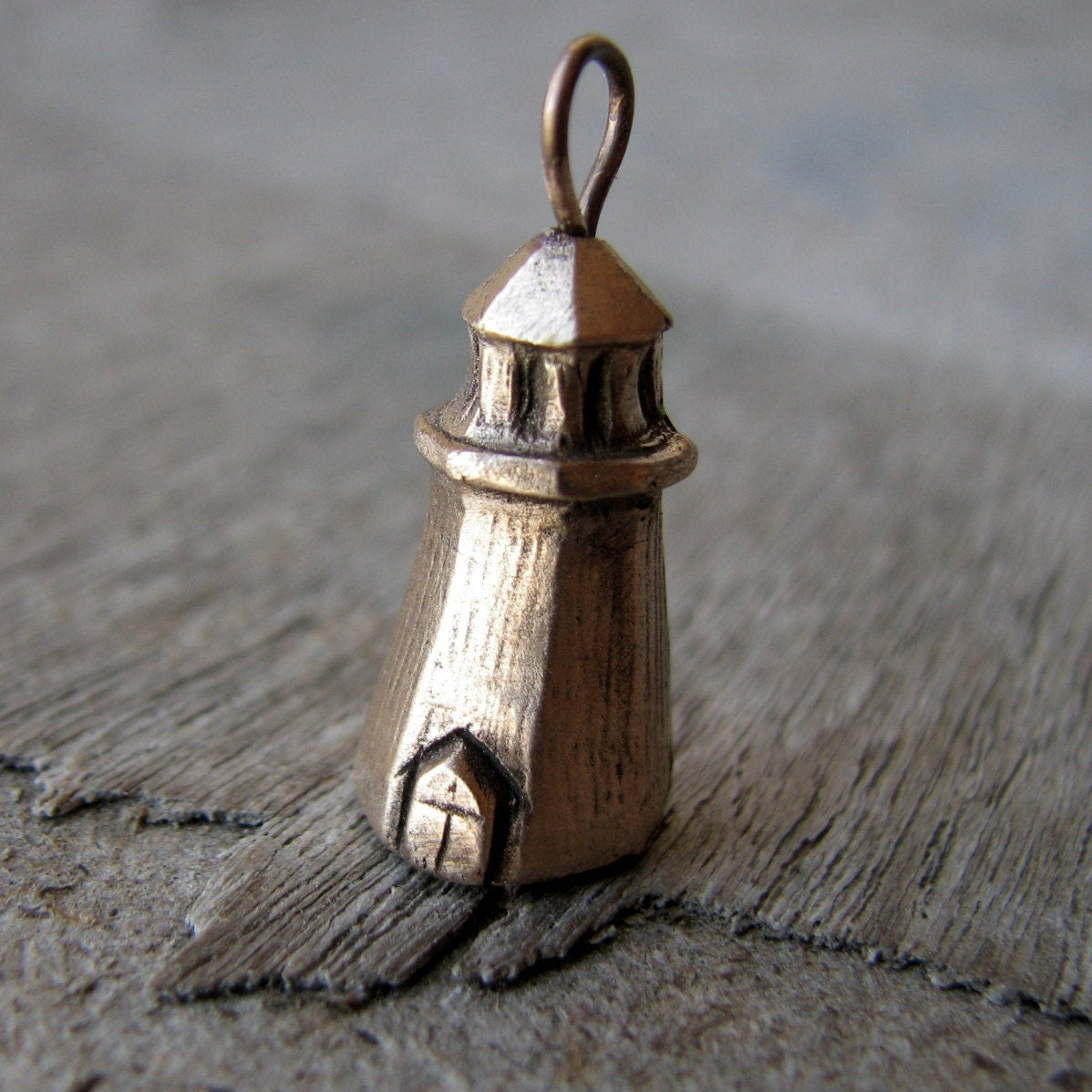 Halsbands hänge med en liten fyr skulpterad i brons