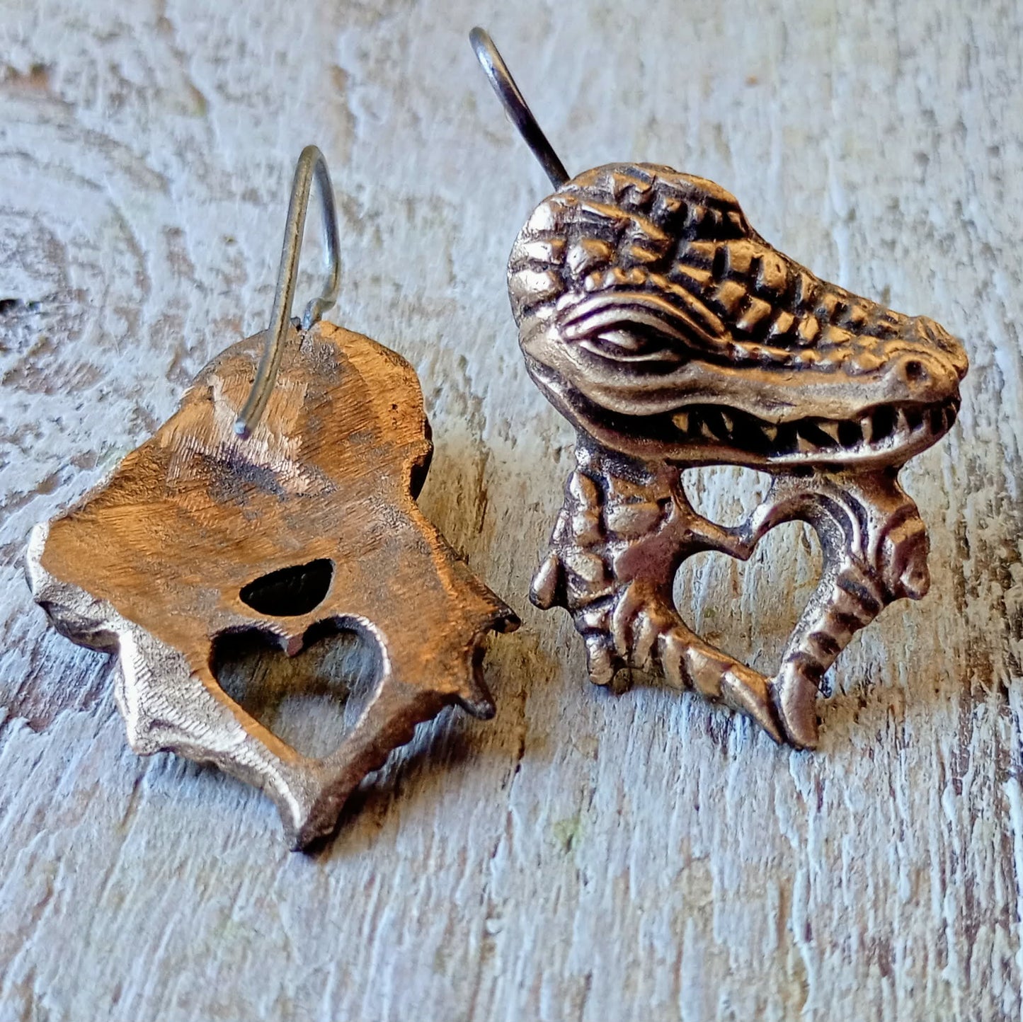 Bronze crocodile earring on a wooden surface