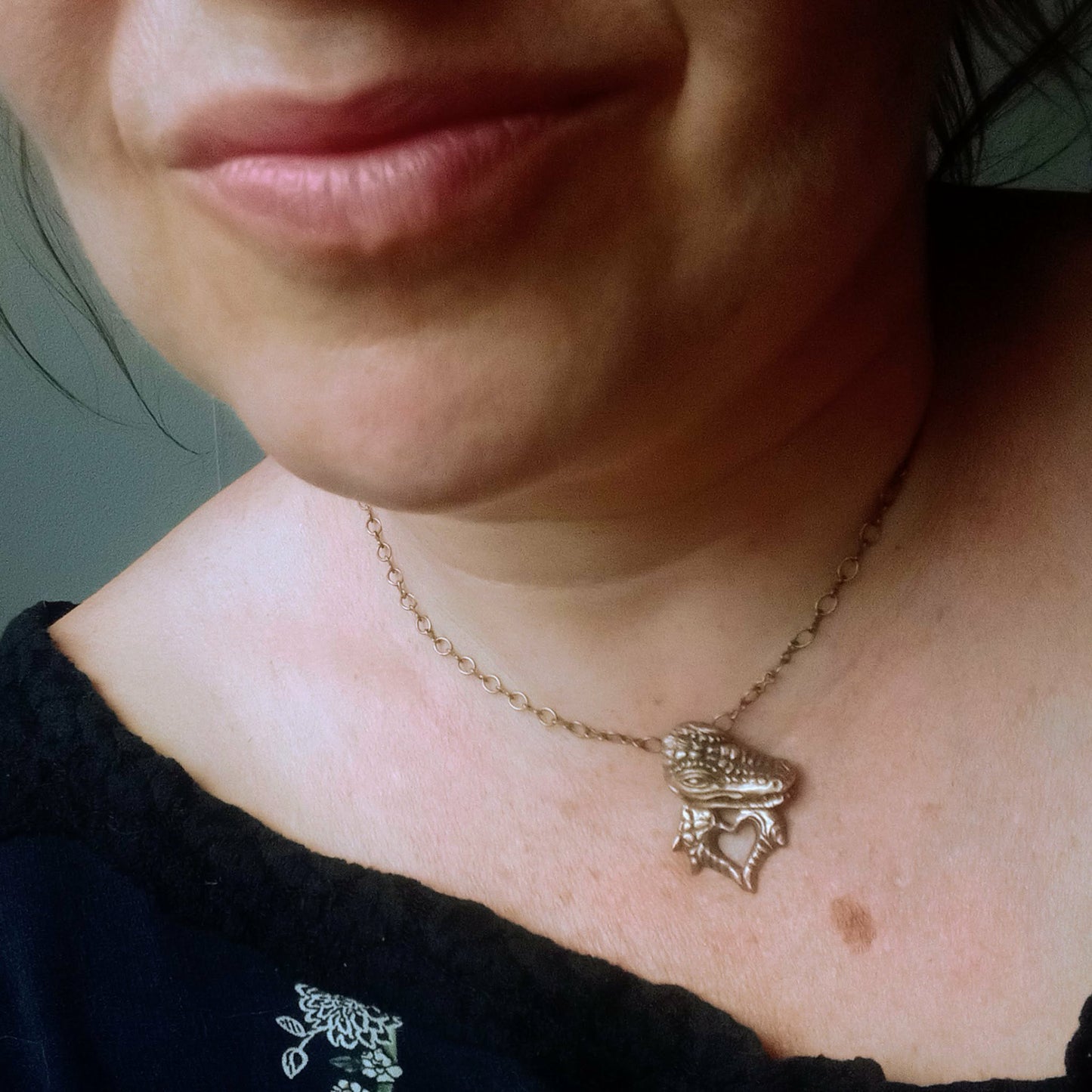 halsband , på skaparen Anna Siivonens hals, med en krokodil skulpterad i brons, krokodilen formar ett hjärta med sina händet/klor