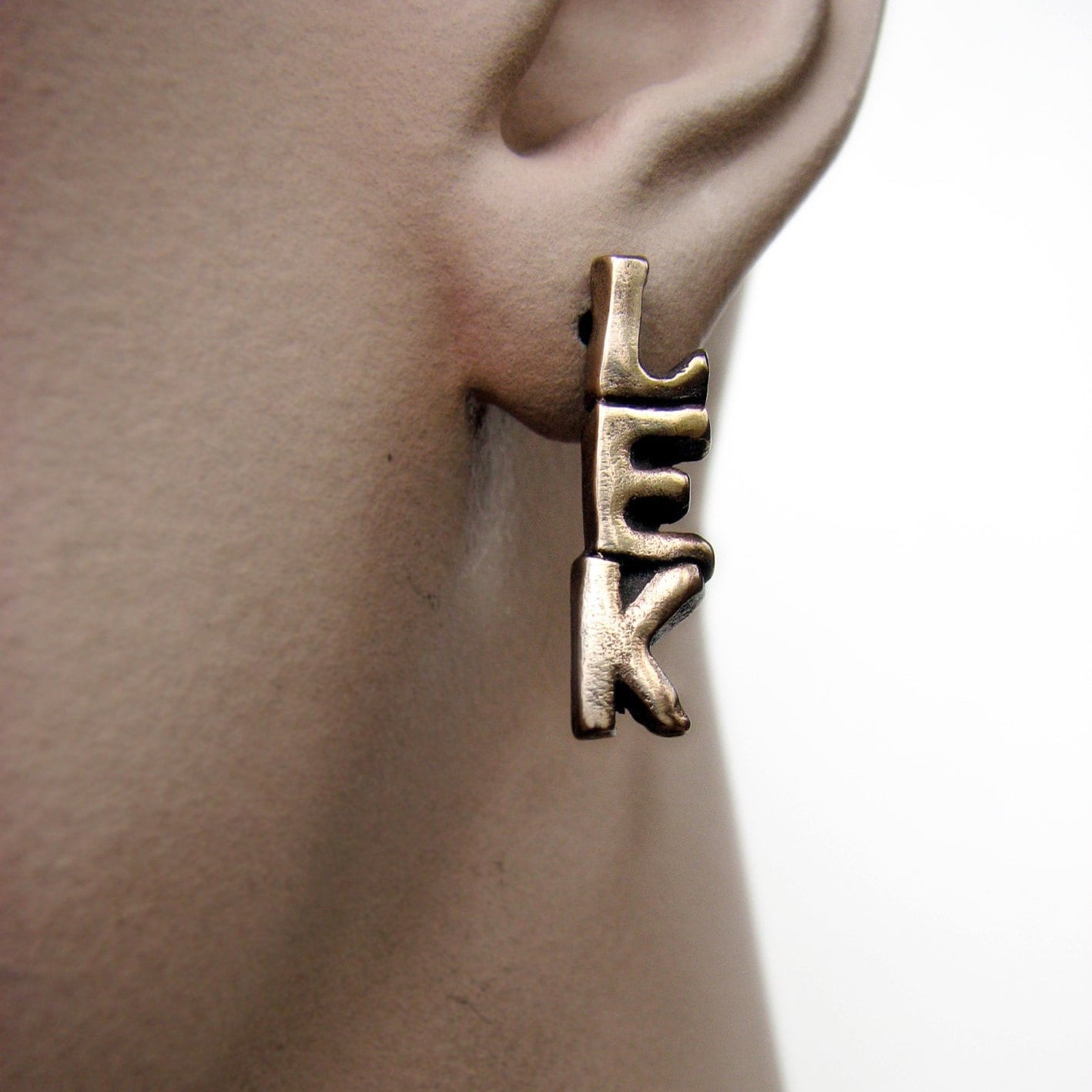 ett örhänge med ordet lek, på modell, 