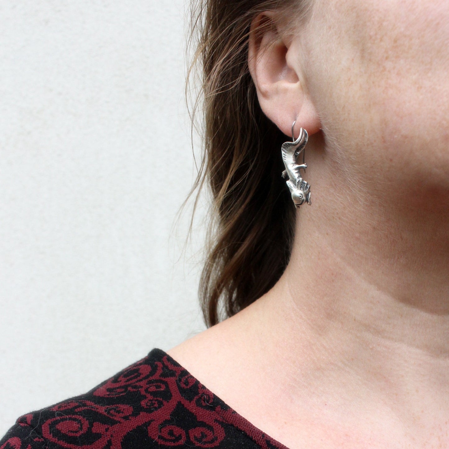 axolot örhänge i sterling silver med titan krok hänger från modells öra