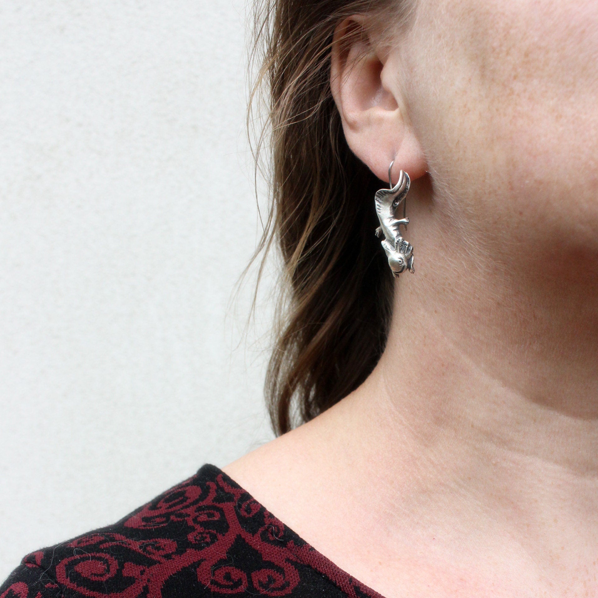 axolot örhänge i sterling silver med titan krok hänger från modells öra