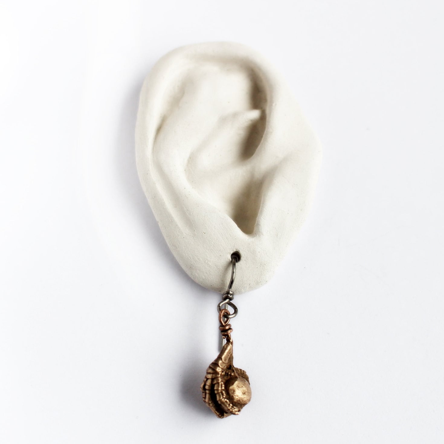 Earring with a bird claw grasping a bead on a white ear model with a white background