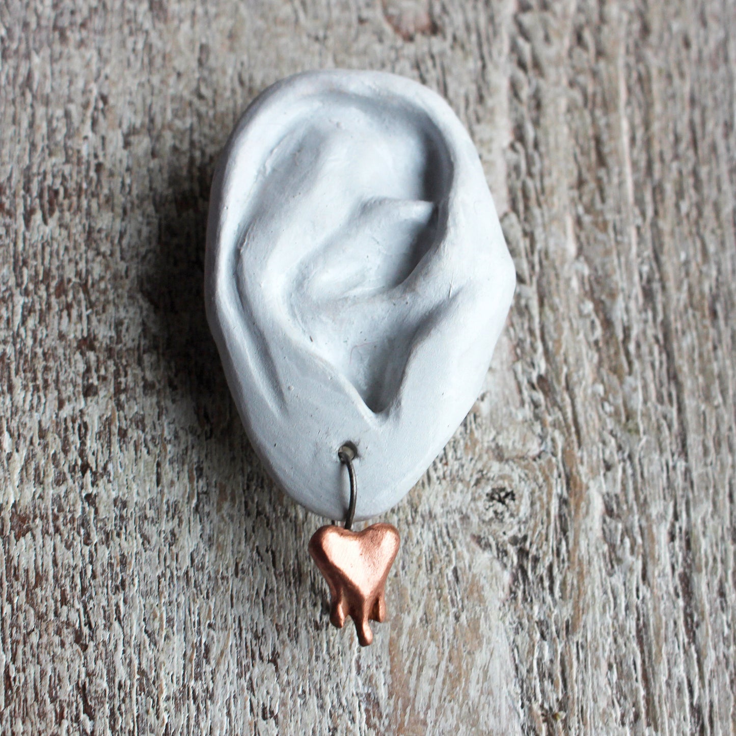 titanörhängen med blödande hjärtan skulpterade i rosa koppar, hjärtana ser ut att vara på väg att smälta eller droppa