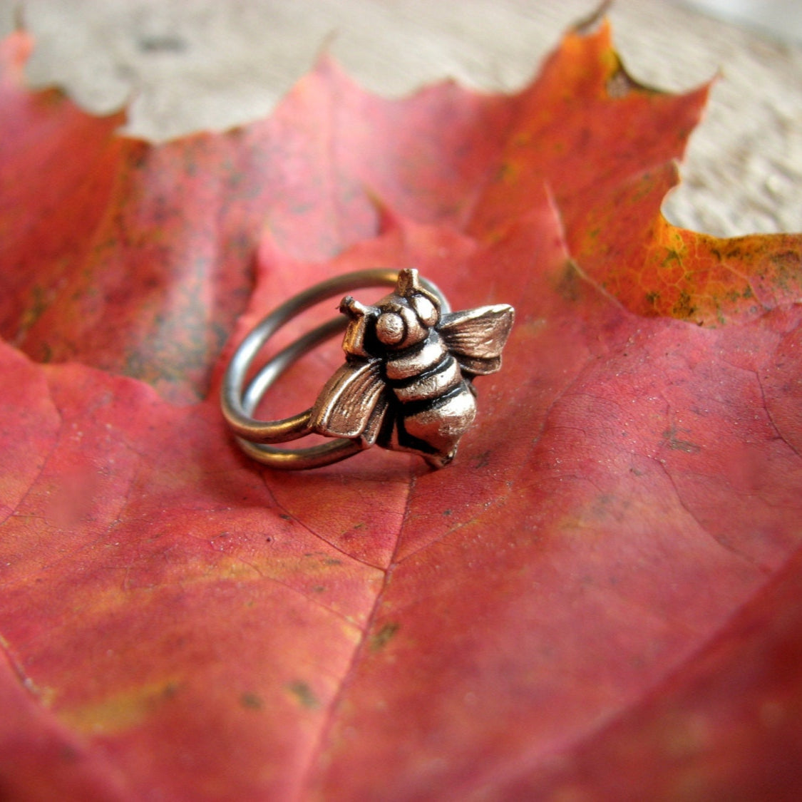Bronze bee ring on a red autumn leaf