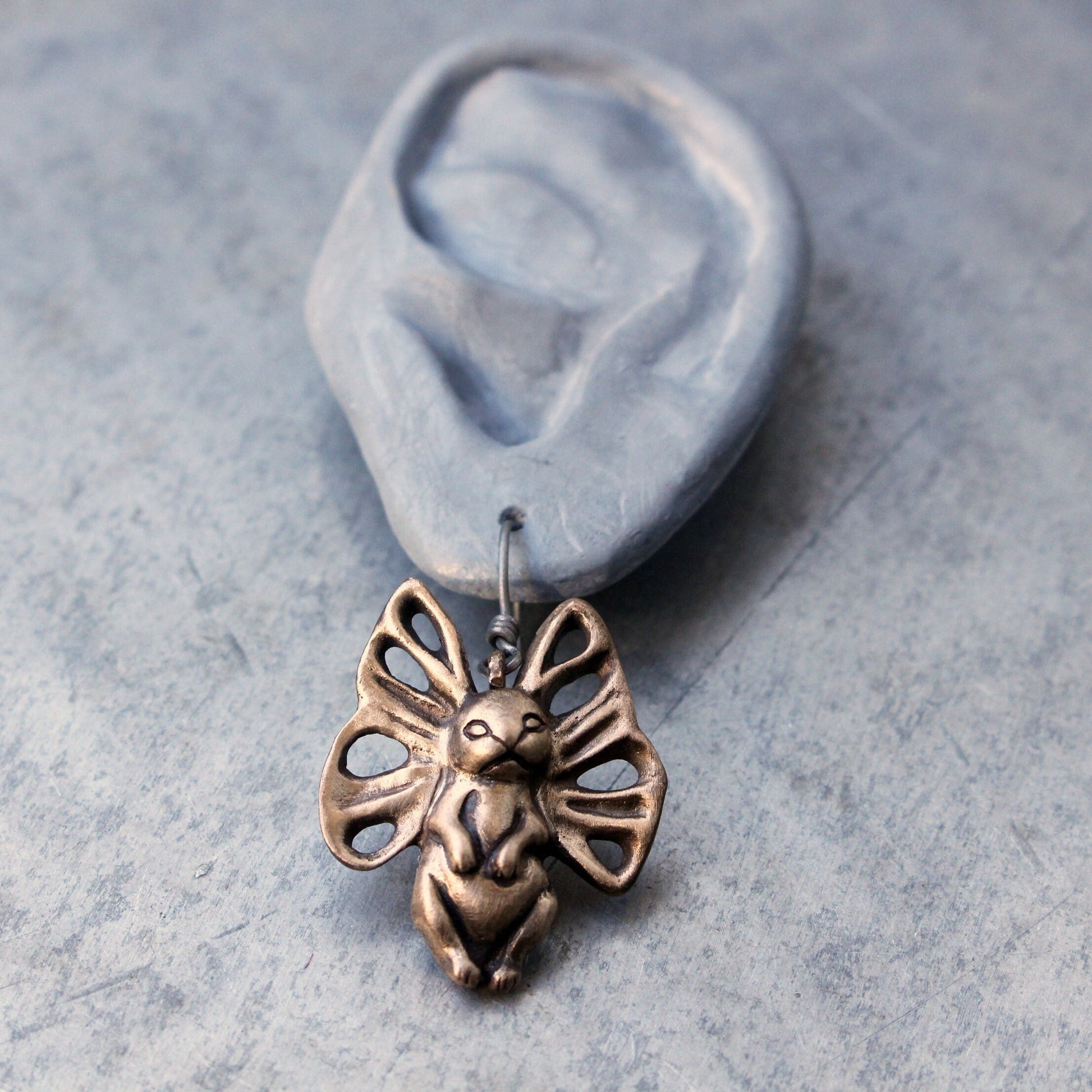 bronze earring with a bunny -fly creature with butterfly wings for ears