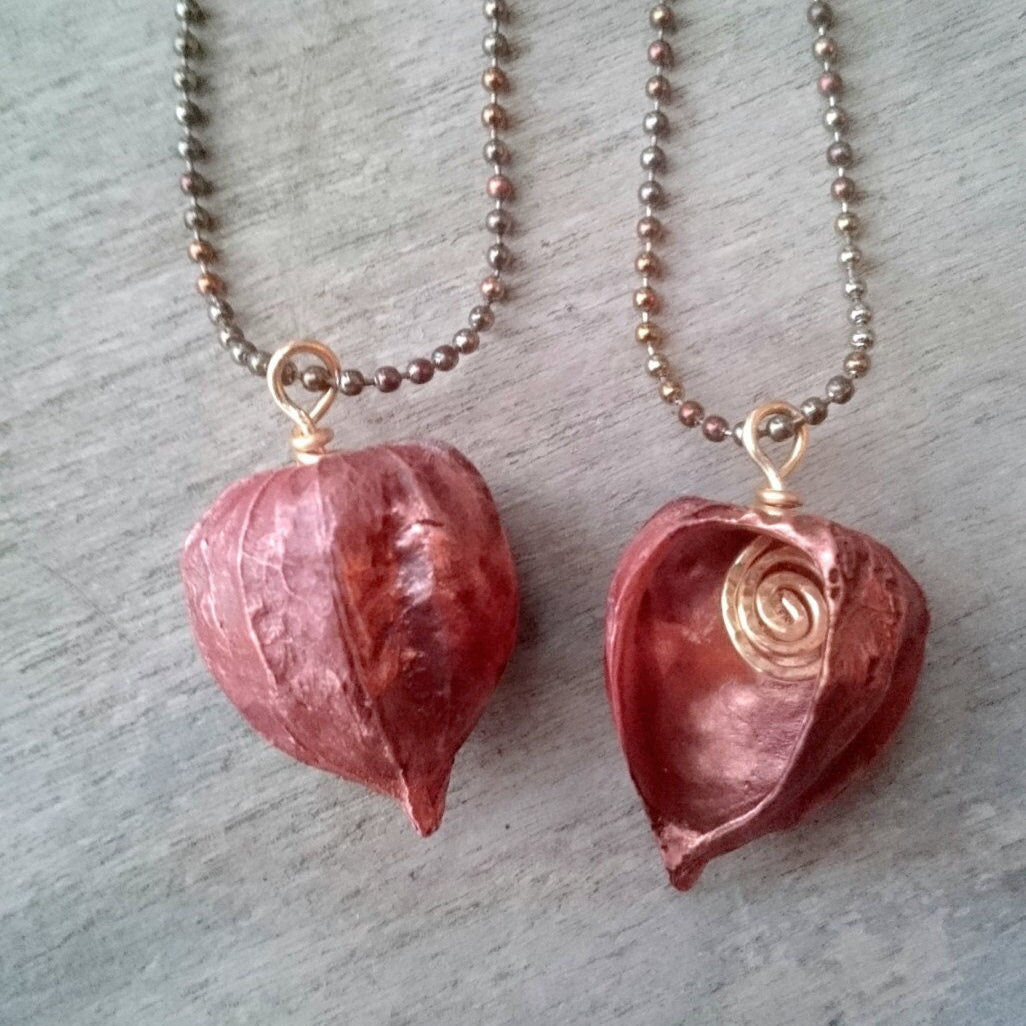 Two copper pendants in the shape of Chinese lanterns or winter cherries, with one showing the front and the other showing the side, both with a ball chain necklace.