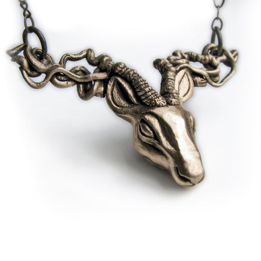 Bronze deer head necklace with sculpted antlers resembling tree roots, attached to an adjustable brass chain.