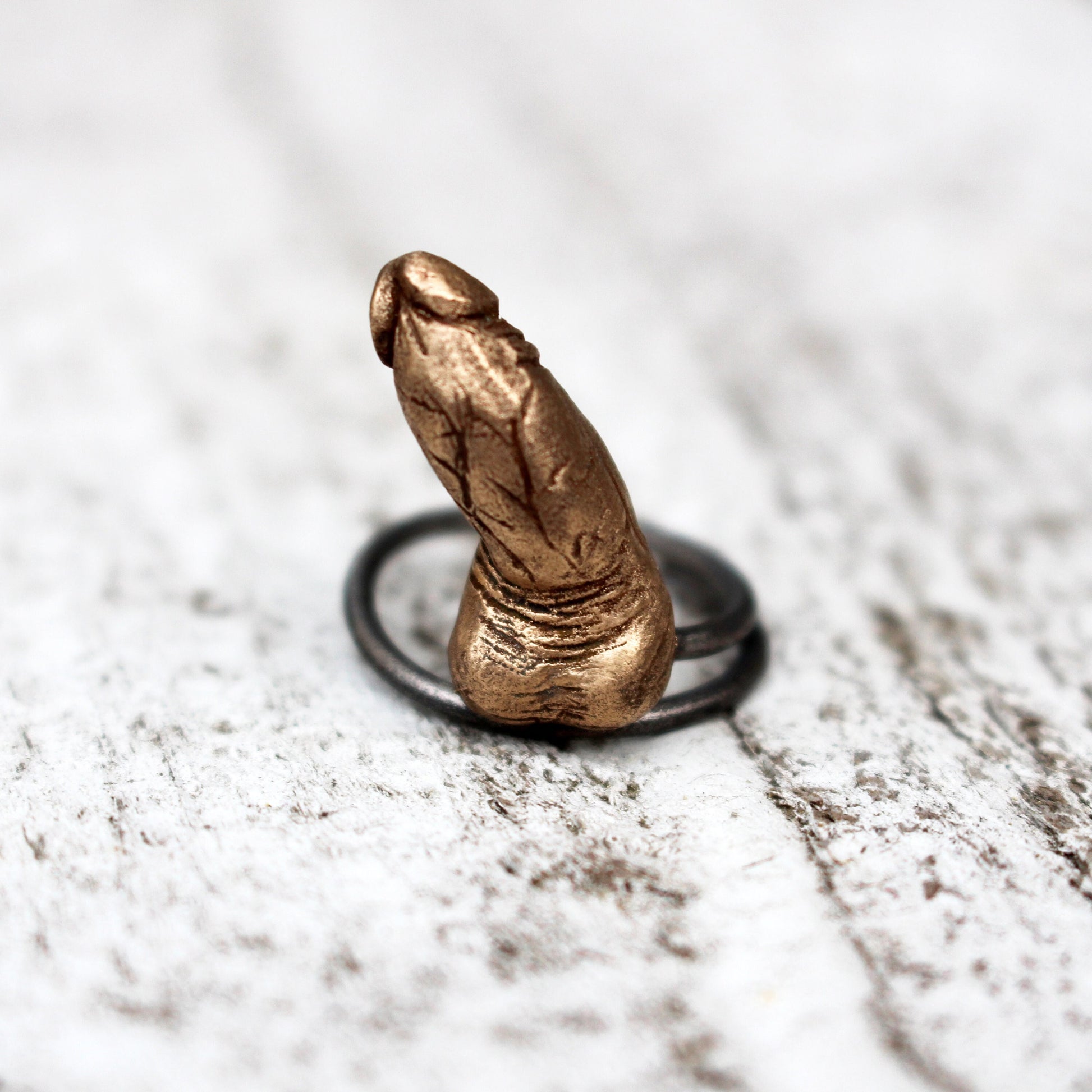  Unique and artistic ring, crafted with a bronze sculpture of an erected penis. The ring is set on a sleek, stainless steel band 