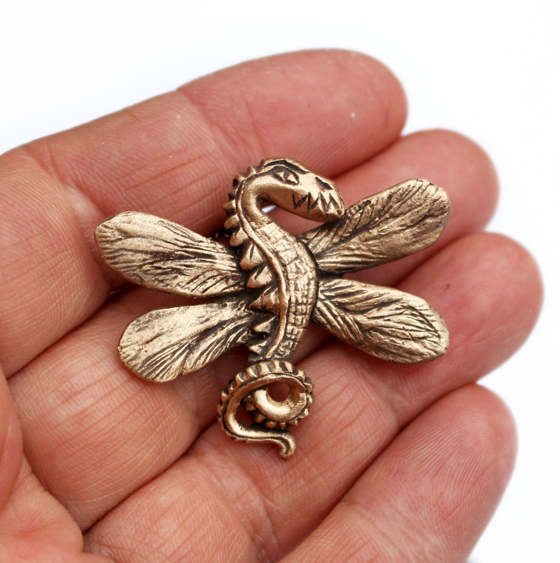 A bronze necklace in the shape of a minature dragon with dragonfly wings